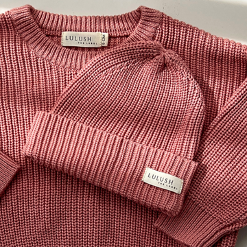Pink knitted sweater and beanie set on a light background
