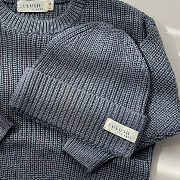 Blue knitted sweater with brand label on a light background