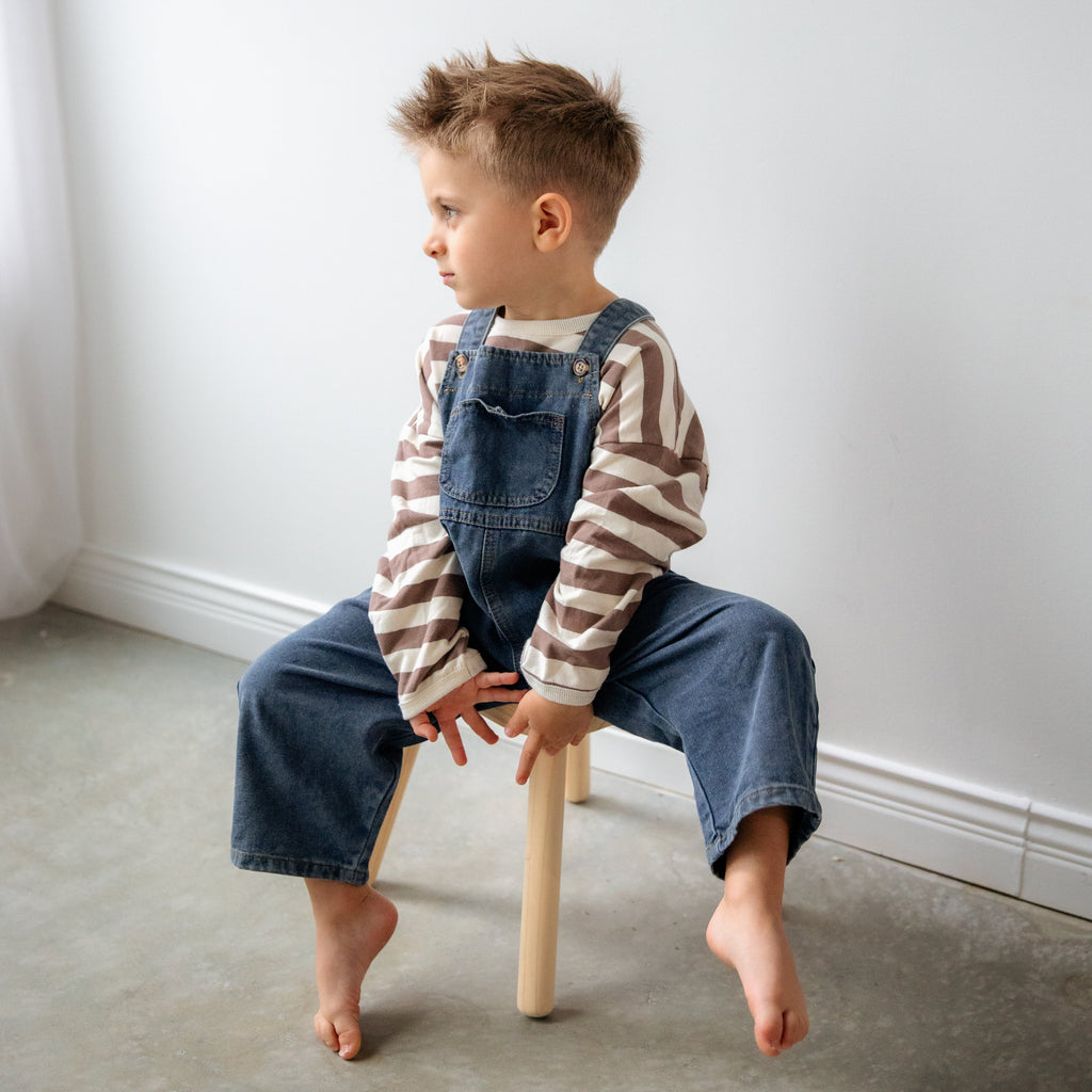 Child sitting on a small stool against a white wall