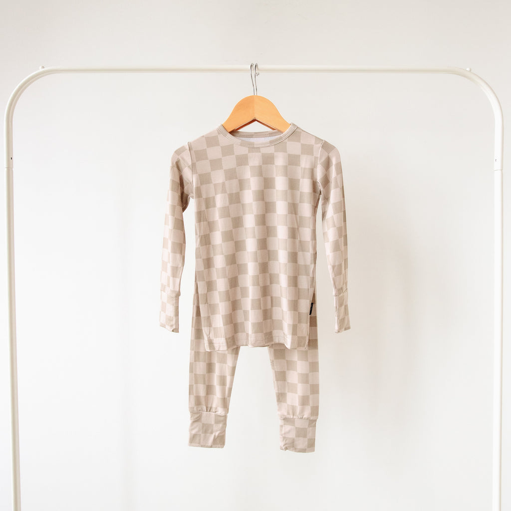 Children's checkered onesie on a hanger against a white background