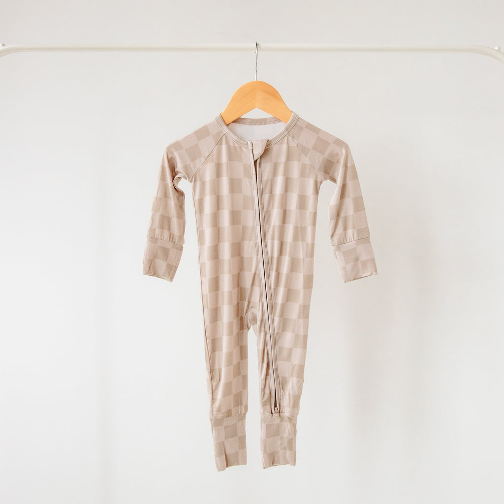 Beige striped baby onesie on a wooden hanger against a white background