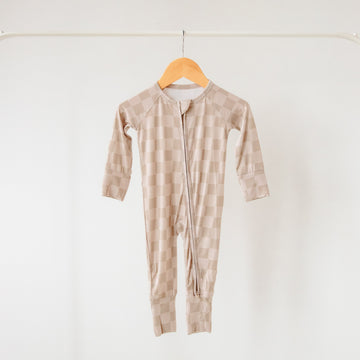 Beige striped baby onesie on a wooden hanger against a white background
