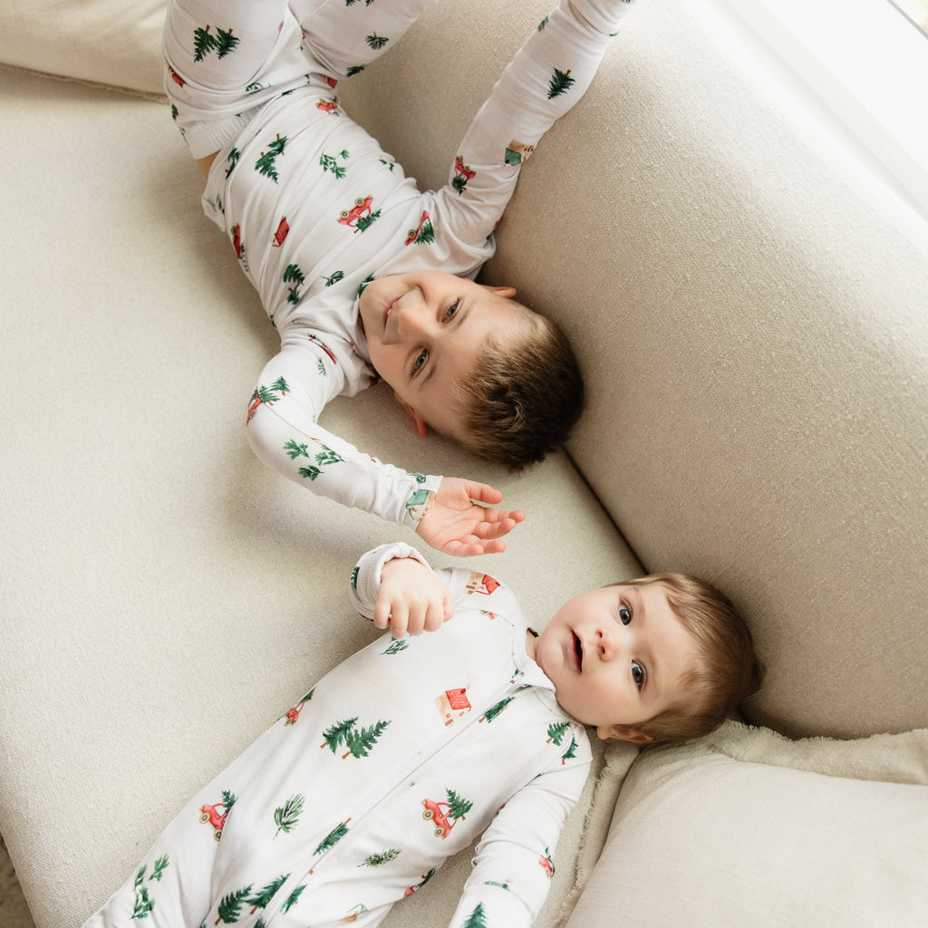 Two children in matching pajamas lying on a couch.