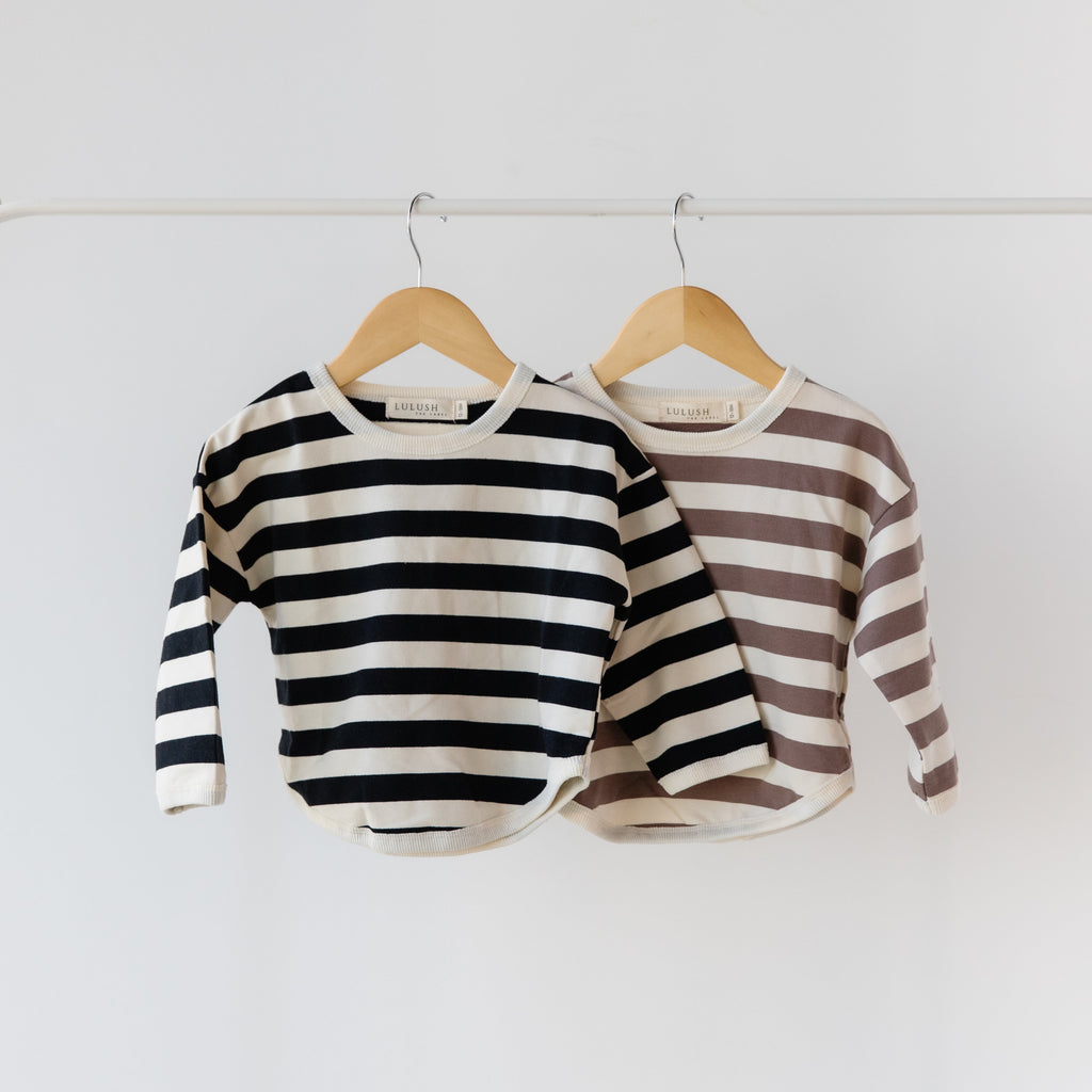 Two striped sweaters hanging on wooden hangers against a white background