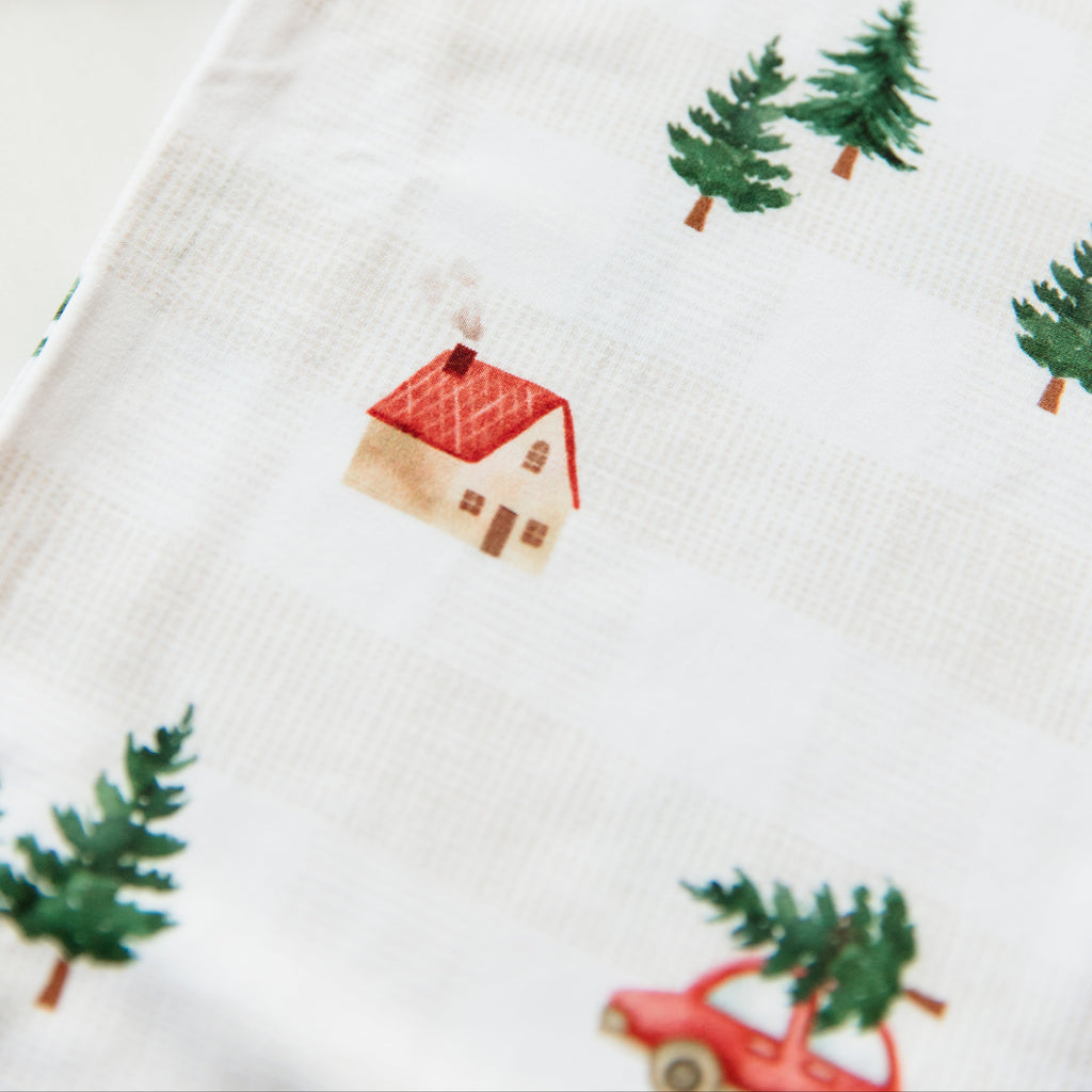 Close-up of fabric with Christmas-themed pattern including houses, trees, and cars.